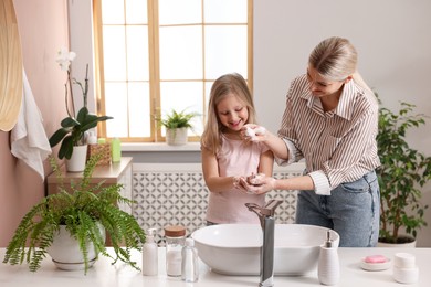 Photo of Happy mother and daughter washing their hands in bathroom