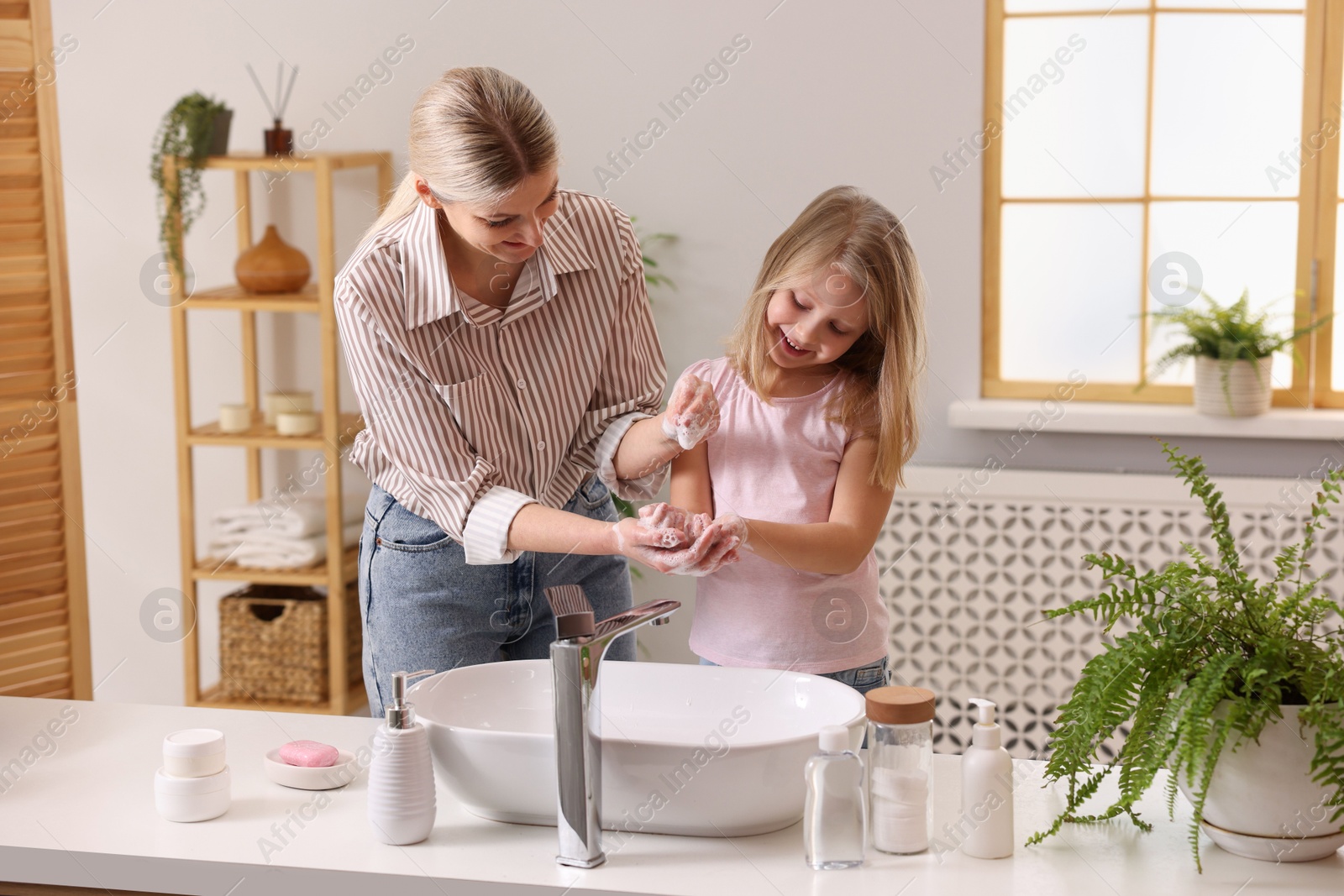 Photo of Happy mother and daughter washing their hands in bathroom