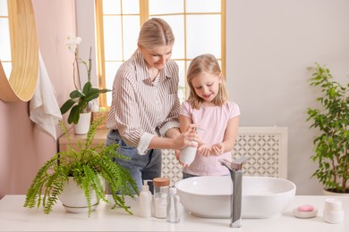 Photo of Happy mother and daughter washing their hands in bathroom