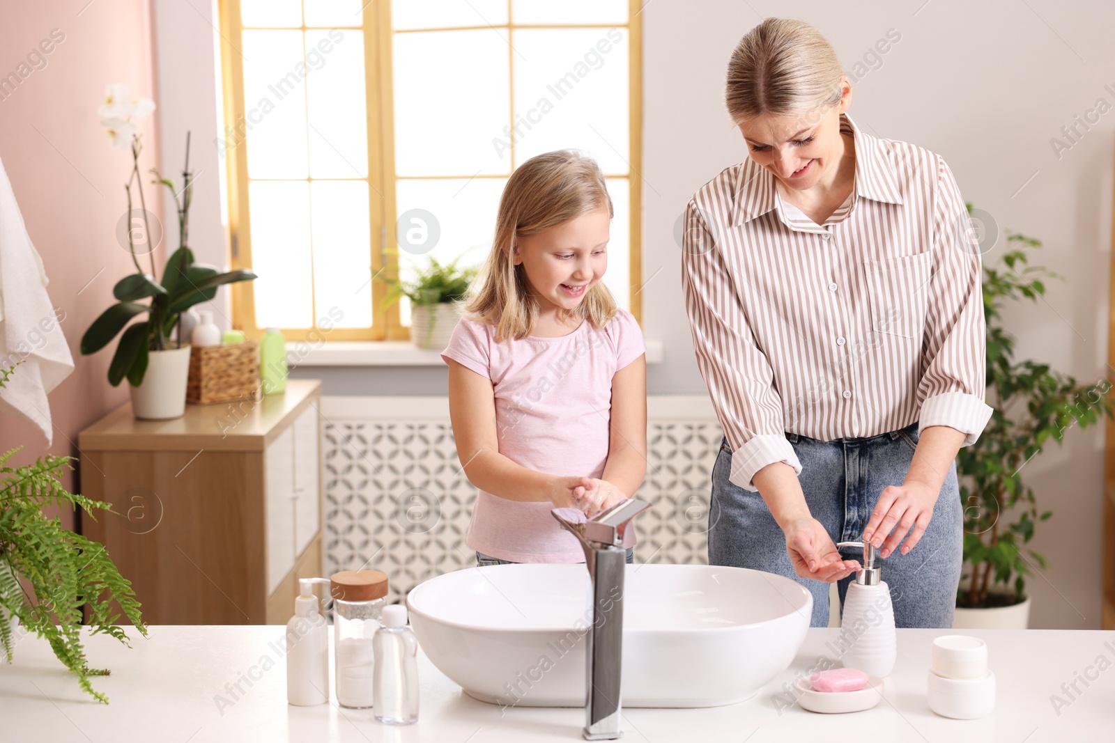 Photo of Happy mother and daughter washing their hands in bathroom