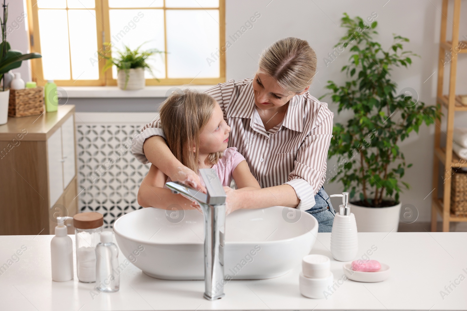 Photo of Mother and daughter washing their hands in bathroom