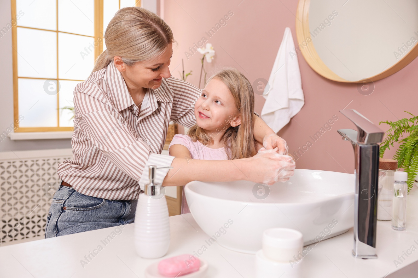 Photo of Happy mother and daughter washing their hands in bathroom