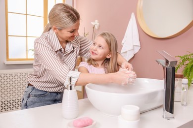 Photo of Happy mother and daughter washing their hands in bathroom