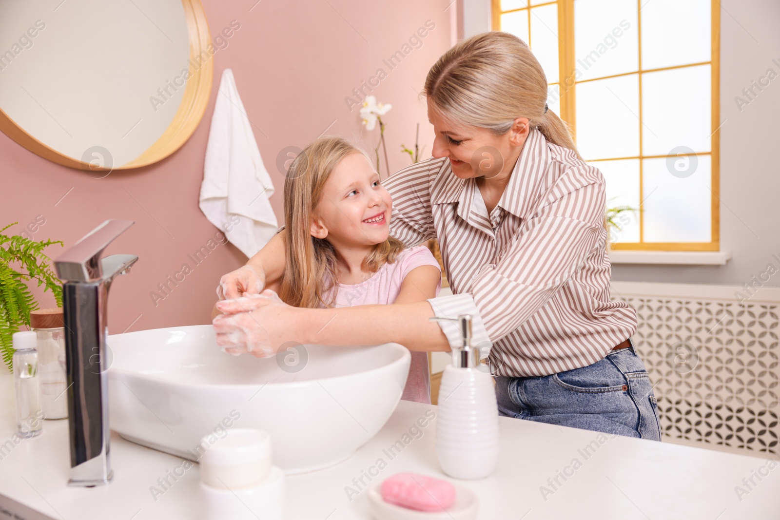 Photo of Happy mother and daughter washing their hands in bathroom