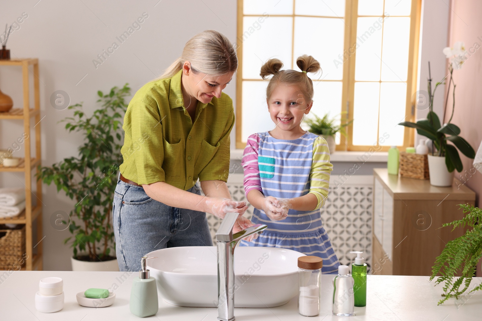 Photo of Happy mother and daughter washing their hands in bathroom