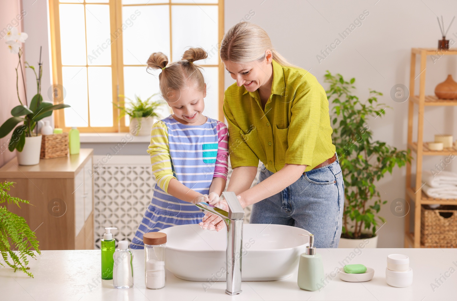 Photo of Happy mother and daughter washing their hands in bathroom