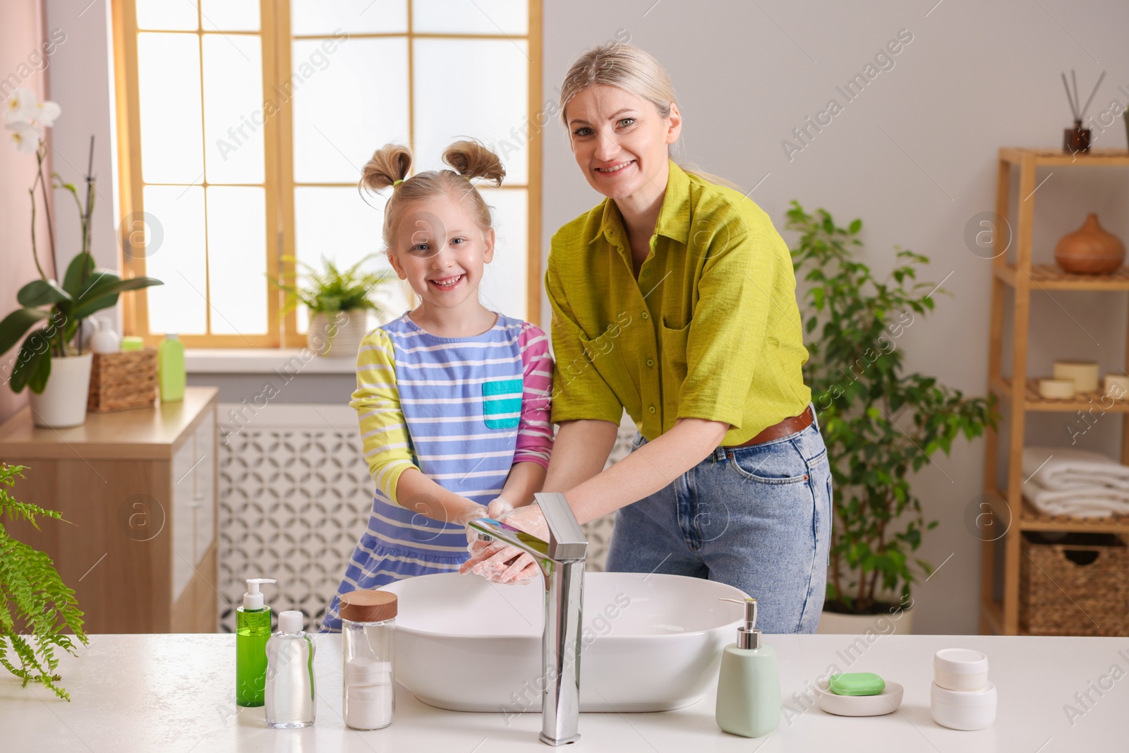 Photo of Happy mother and daughter washing their hands in bathroom