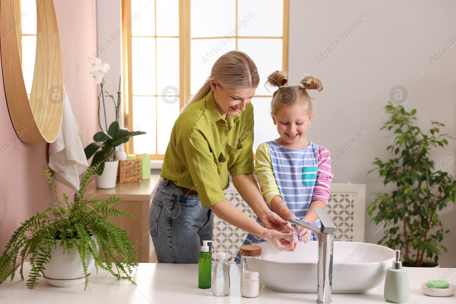 Photo of Happy mother and daughter washing their hands in bathroom