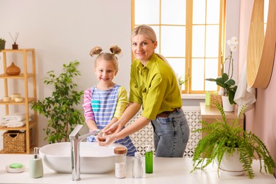 Photo of Happy mother and daughter washing their hands in bathroom