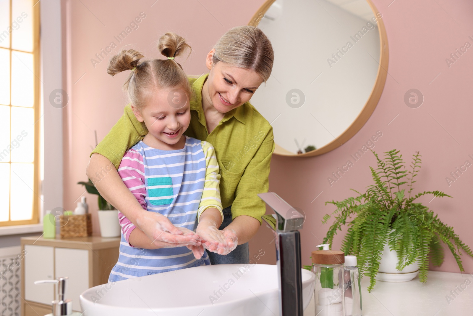 Photo of Happy mother and daughter washing their hands in bathroom