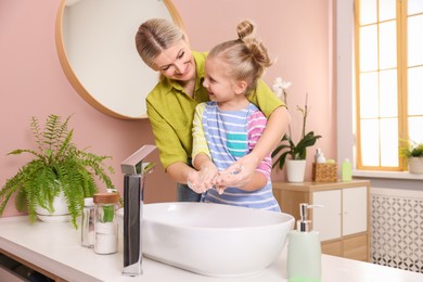 Photo of Happy mother and daughter washing their hands in bathroom