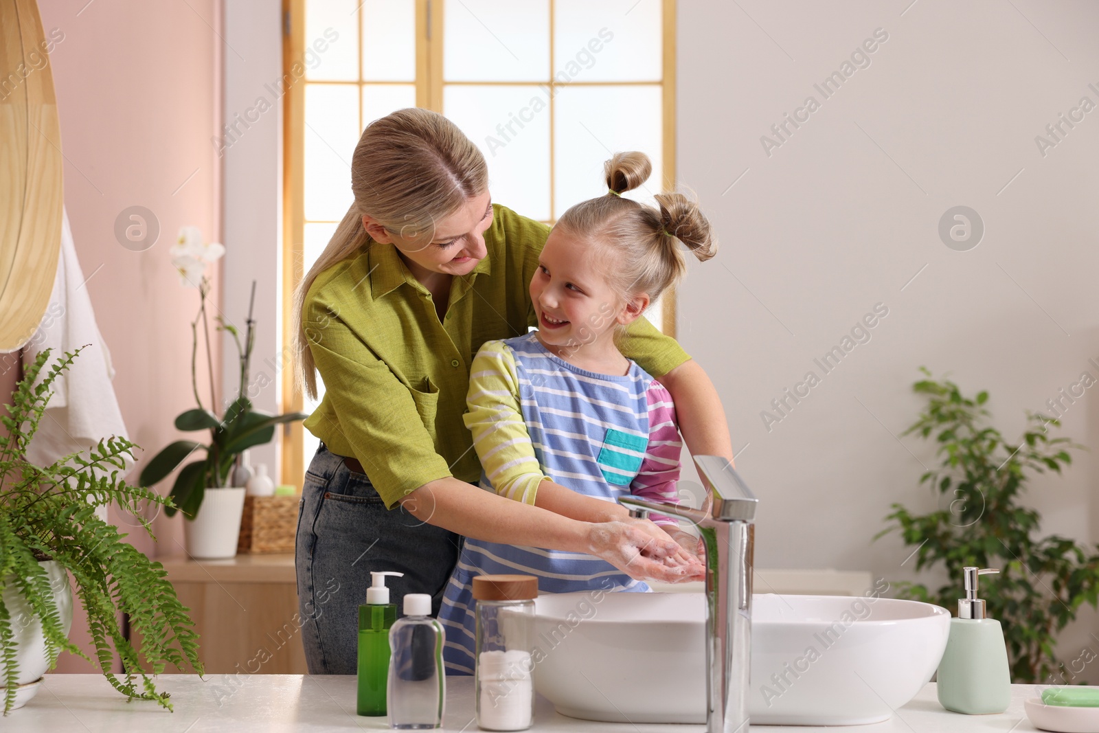 Photo of Happy mother and daughter washing their hands in bathroom