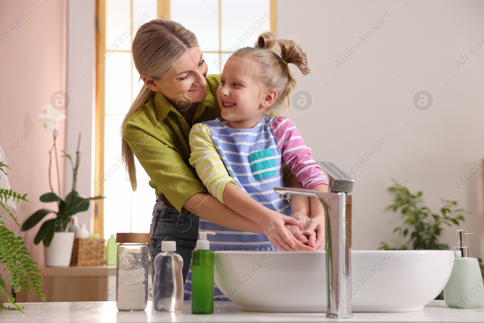 Photo of Happy mother and daughter washing their hands in bathroom