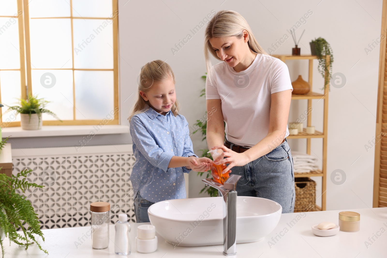 Photo of Happy mother and daughter washing their hands in bathroom