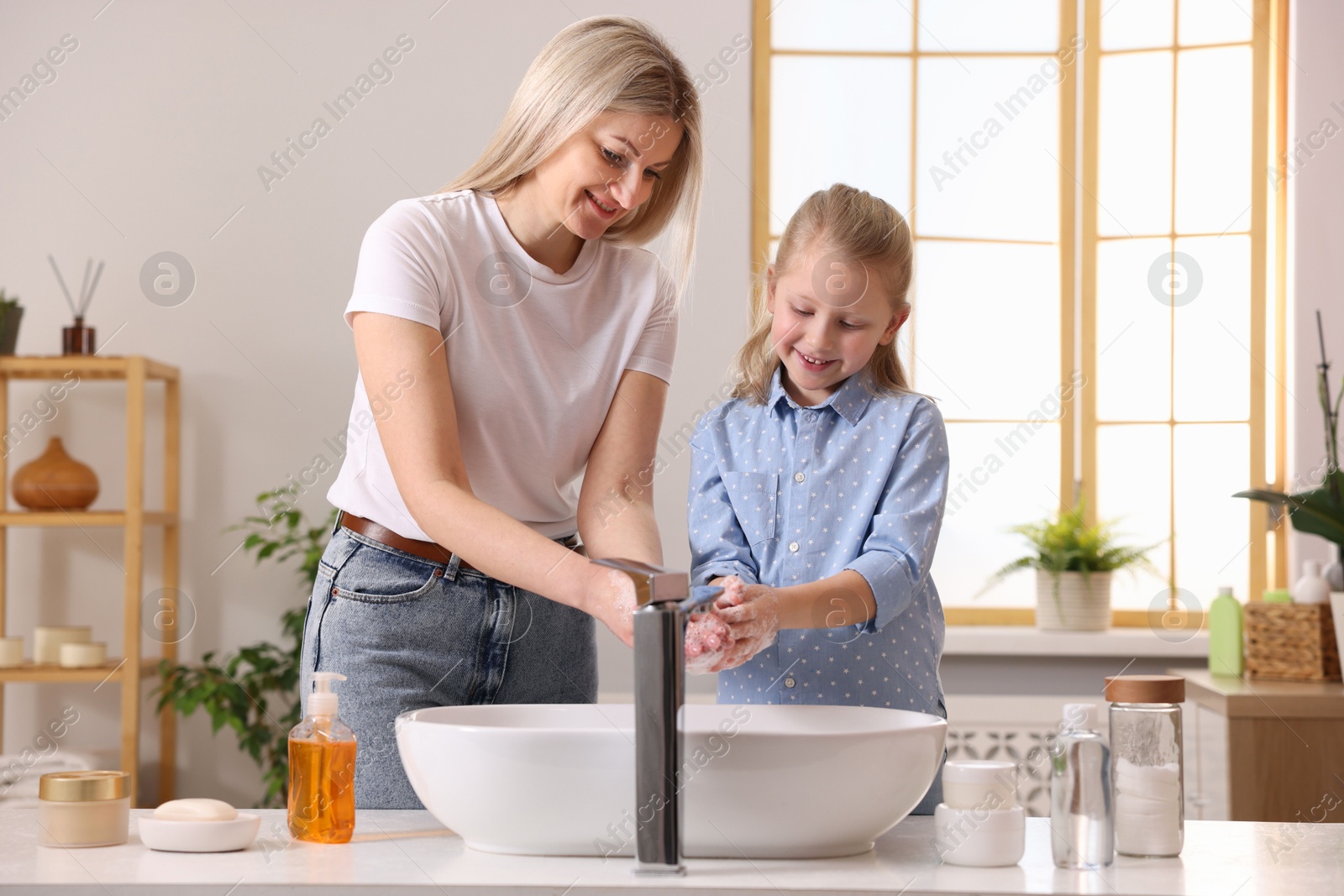 Photo of Happy mother and daughter washing their hands in bathroom