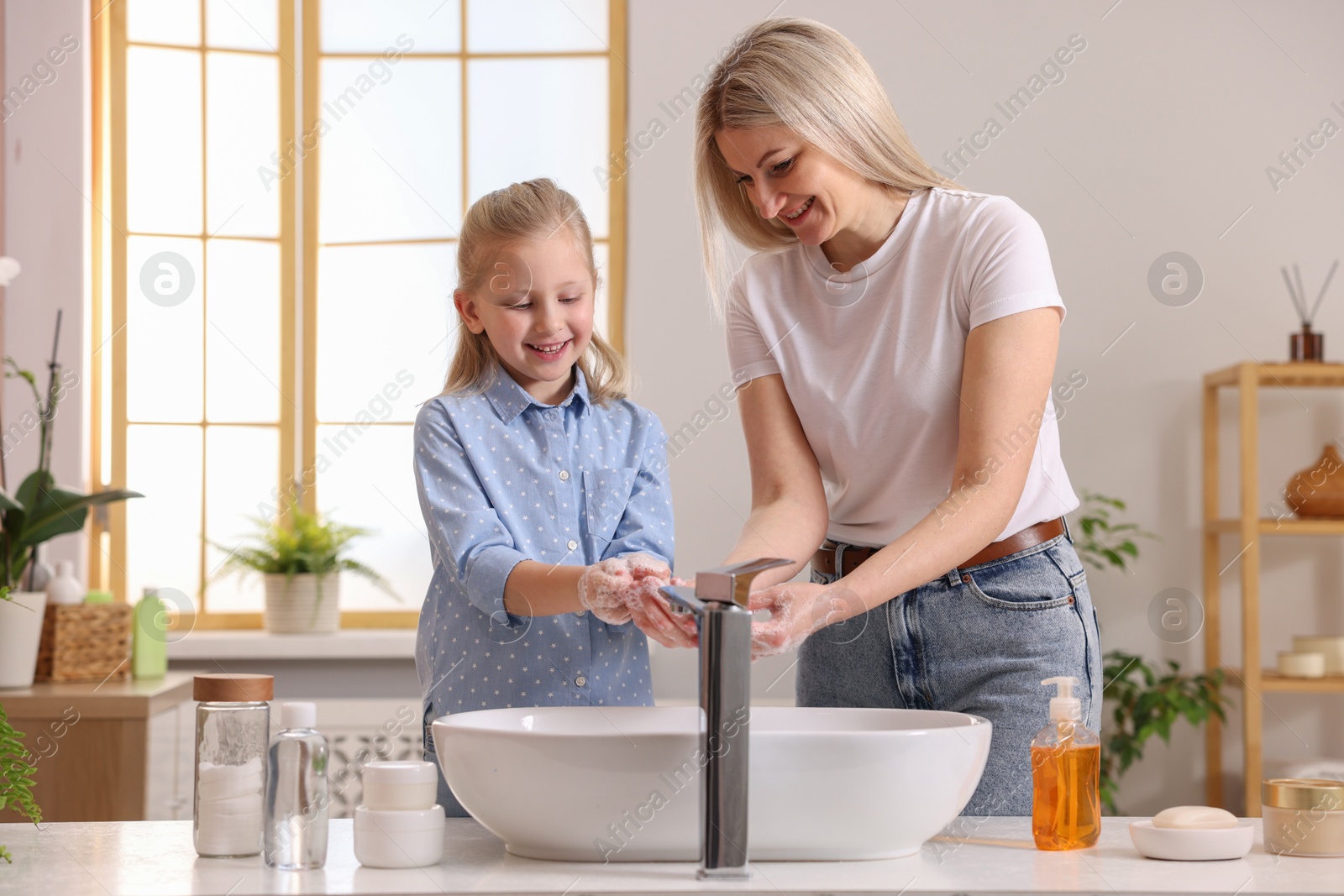 Photo of Happy mother and daughter washing their hands in bathroom