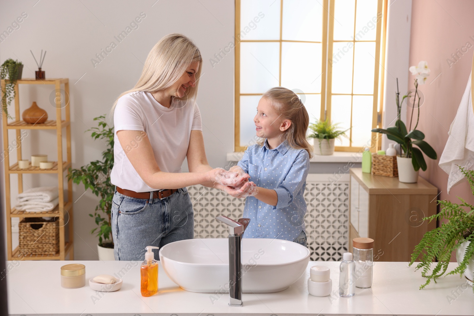 Photo of Happy mother and daughter washing their hands in bathroom