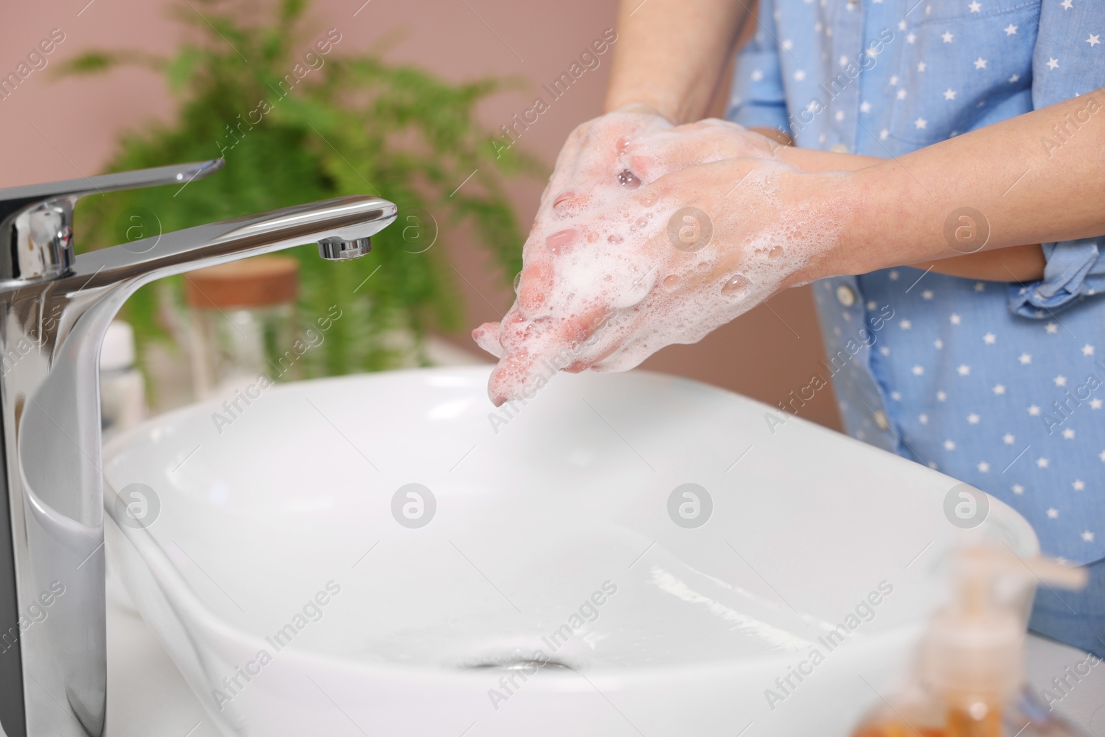 Photo of Mother and daughter washing their hands above sink indoors, closeup