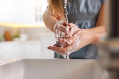 Photo of Mother and daughter washing their hands above sink indoors, closeup. Space for text