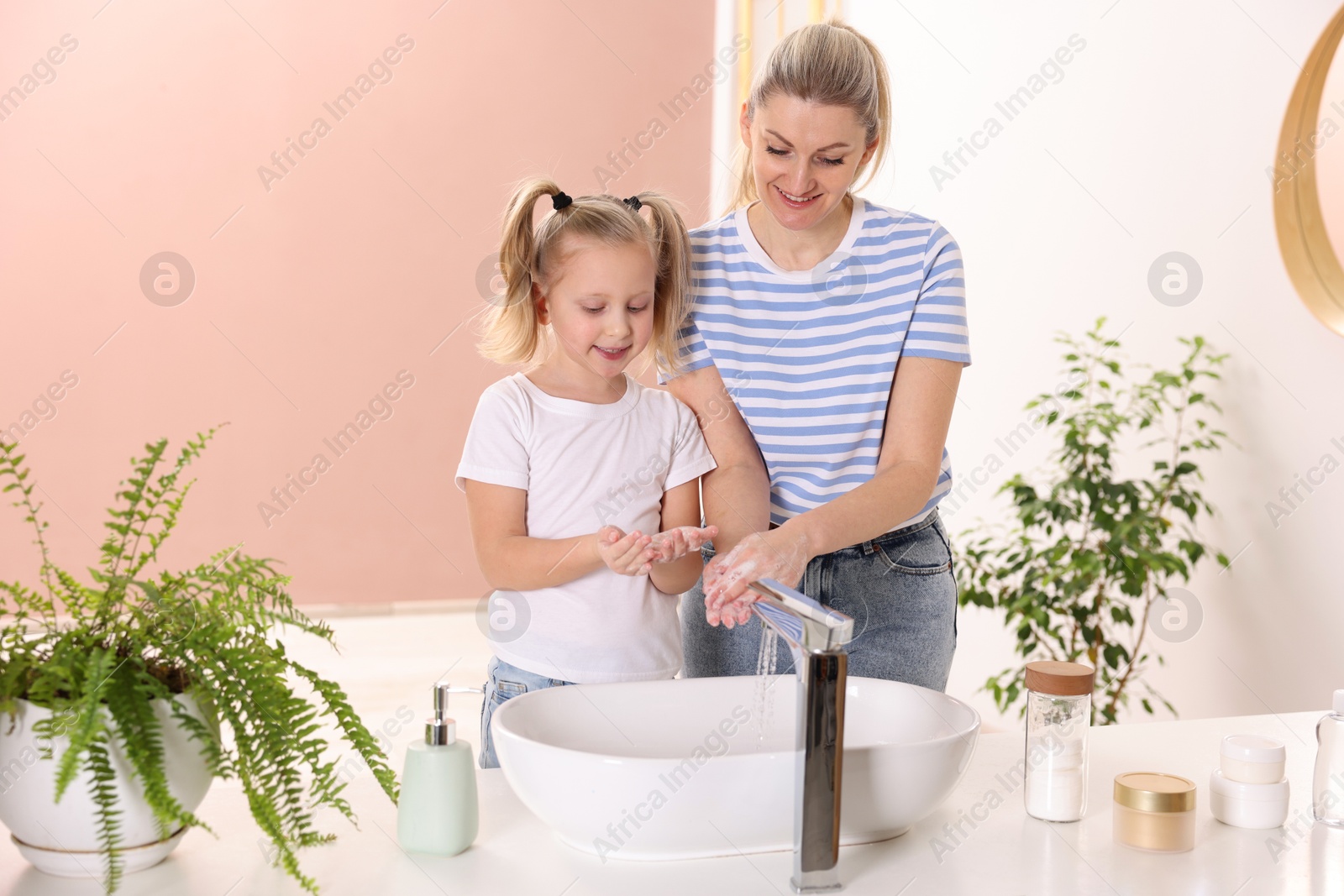 Photo of Happy mother and daughter washing their hands indoors