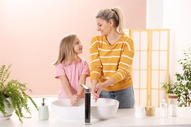 Photo of Happy mother and daughter washing their hands at home