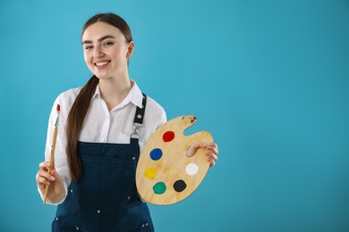 Photo of Smiling woman with wooden palette and paintbrush on light blue background. Space for text