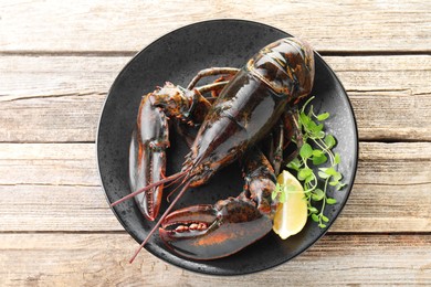 Photo of Raw lobster, piece of lemon and microgreens on wooden table, top view