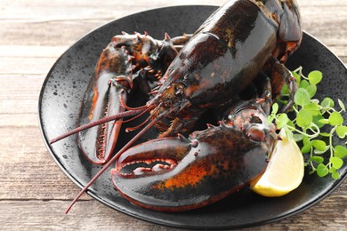 Photo of Raw lobster, piece of lemon and microgreens on wooden table, closeup