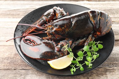 Photo of Raw lobster, piece of lemon and microgreens on wooden table, closeup