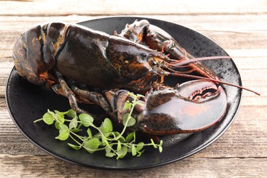 Photo of Raw lobster and microgreens on wooden table, closeup