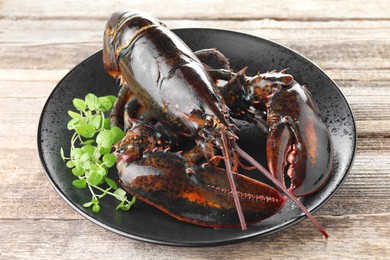 Photo of Raw lobster and microgreens on wooden table, closeup