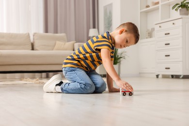 Photo of Little boy playing with toy car at home