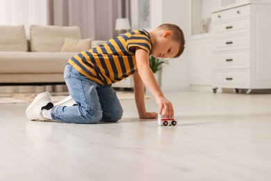 Photo of Little boy playing with toy car at home