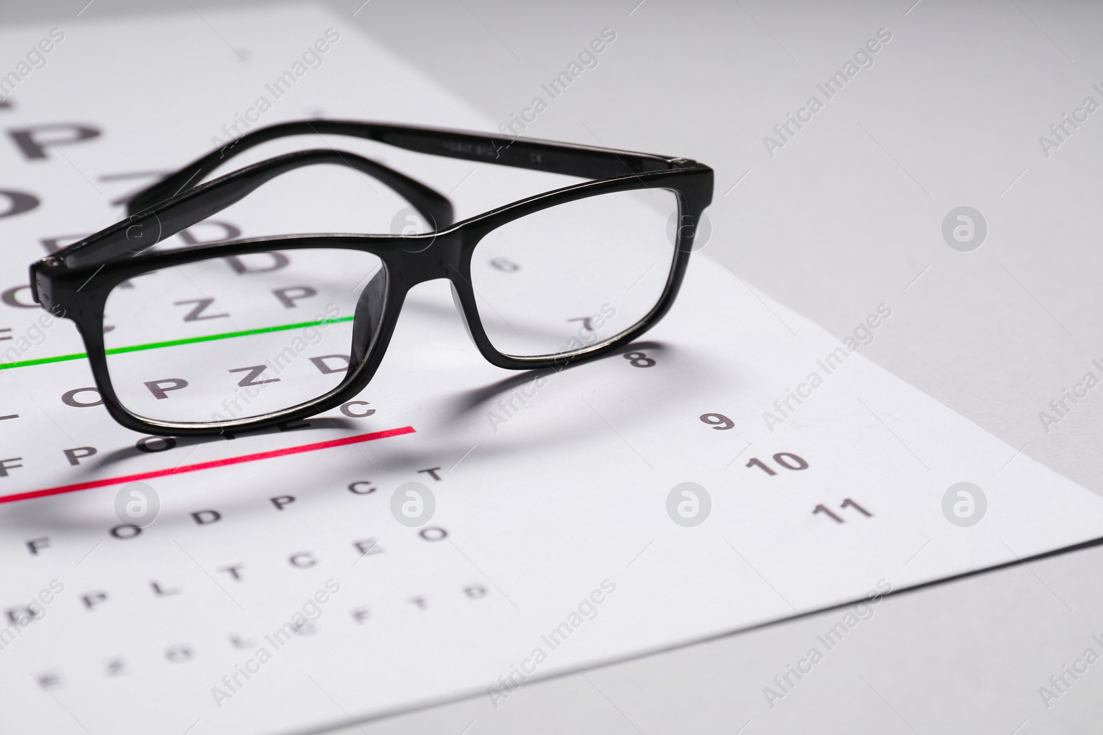 Photo of Glasses and vision test chart on gray background, closeup. Space for text