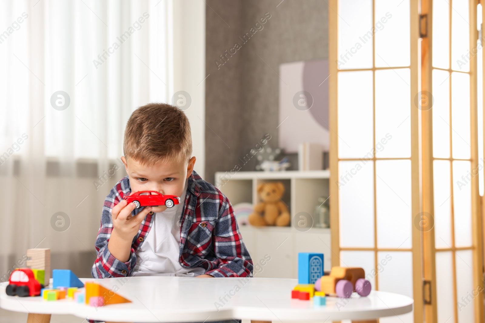 Photo of Little boy playing with toys at table indoors