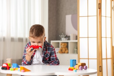 Little boy playing with toys at table indoors