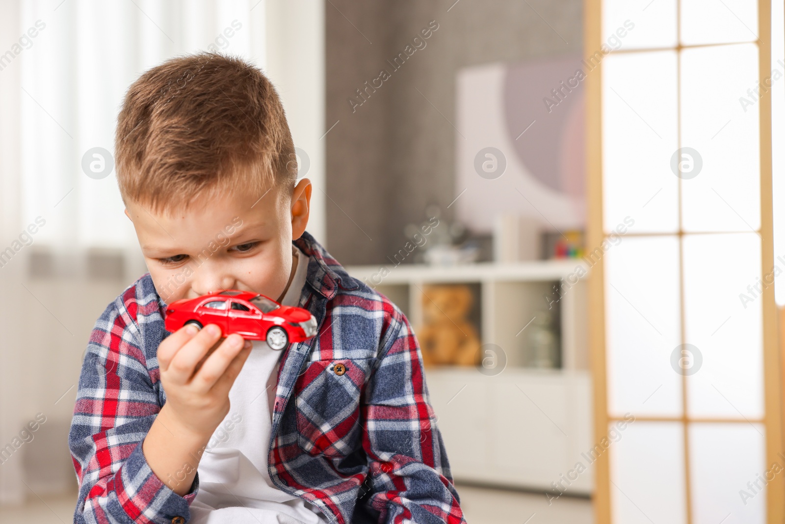 Photo of Little boy playing with toy car at home. Space for text