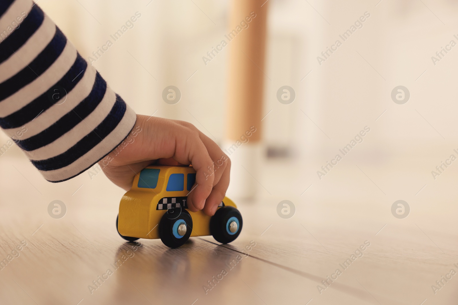 Photo of Little girl playing with toy car on floor at home, closeup. Space for text