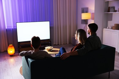 Happy family watching tv together at home in evening