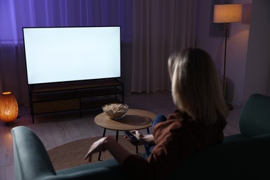 Woman watching tv at home in evening, back view