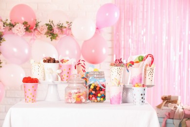 Candy bar. Many different sweets on table in festive decorated room