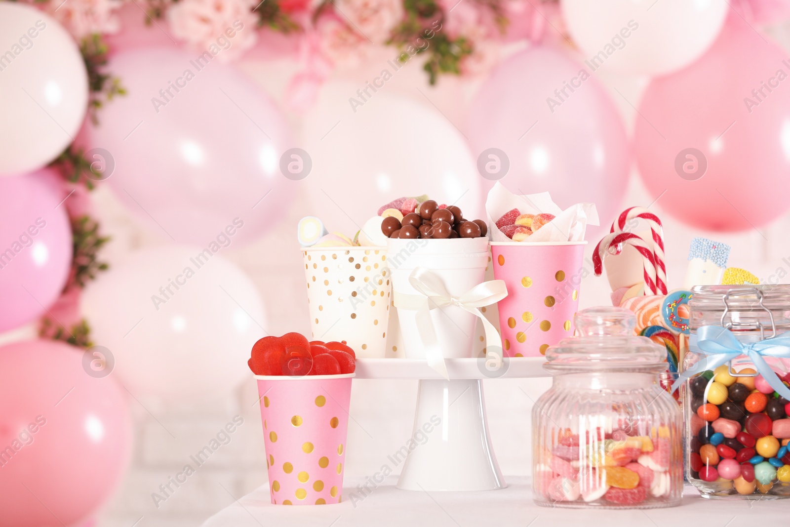 Photo of Candy bar. Many different sweets on table in festive decorated room, space for text