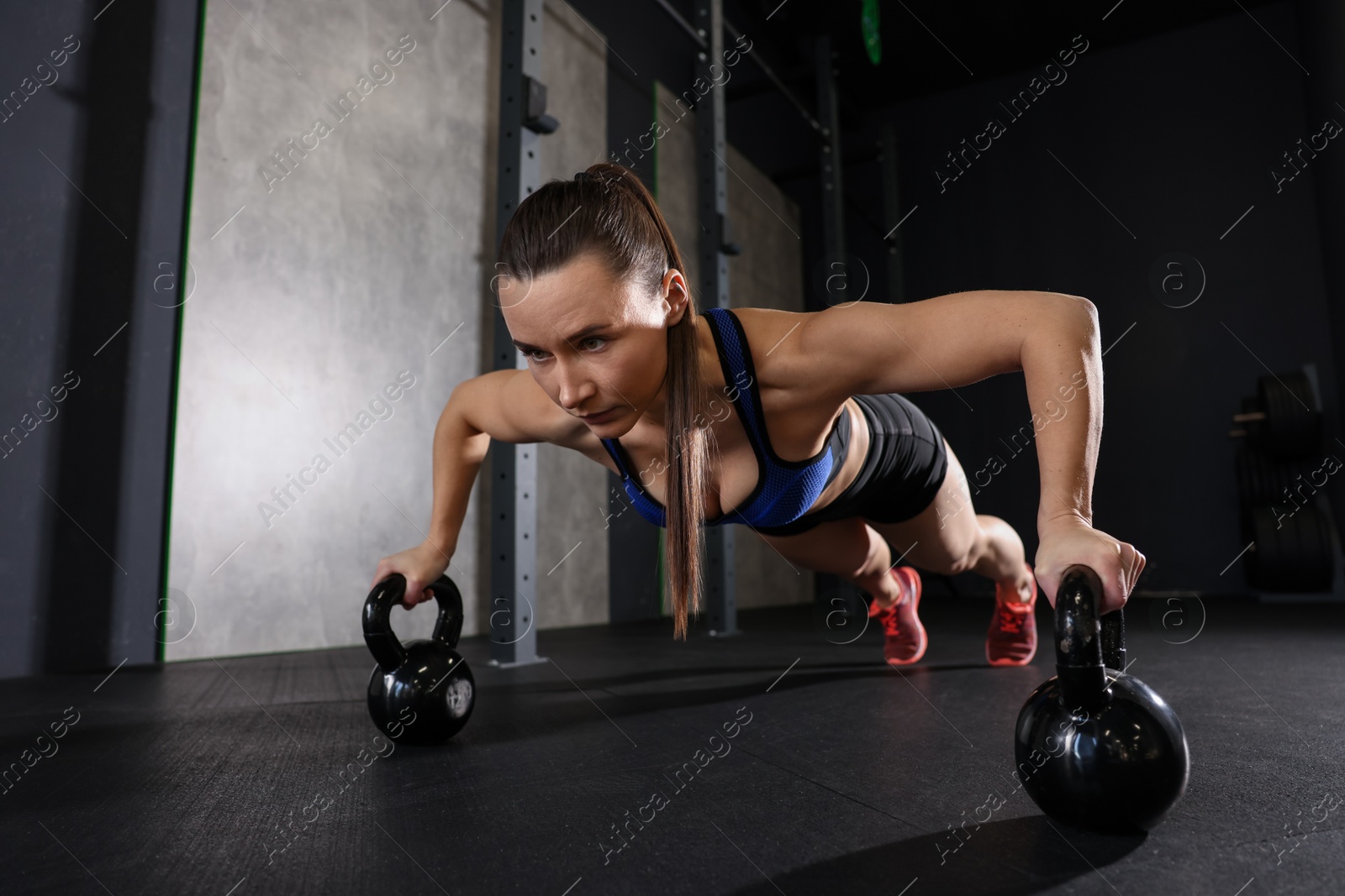 Photo of Sportswoman doing kettlebell push up during crossfit workout in gym