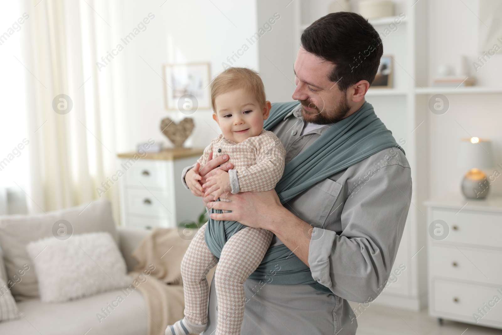 Photo of Father holding his child in sling (baby carrier) at home, space for text