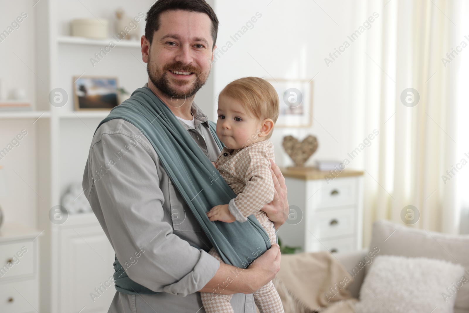 Photo of Father holding his child in sling (baby carrier) at home, space for text