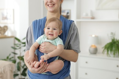 Photo of Mother holding her child in sling at home, closeup. Space for text