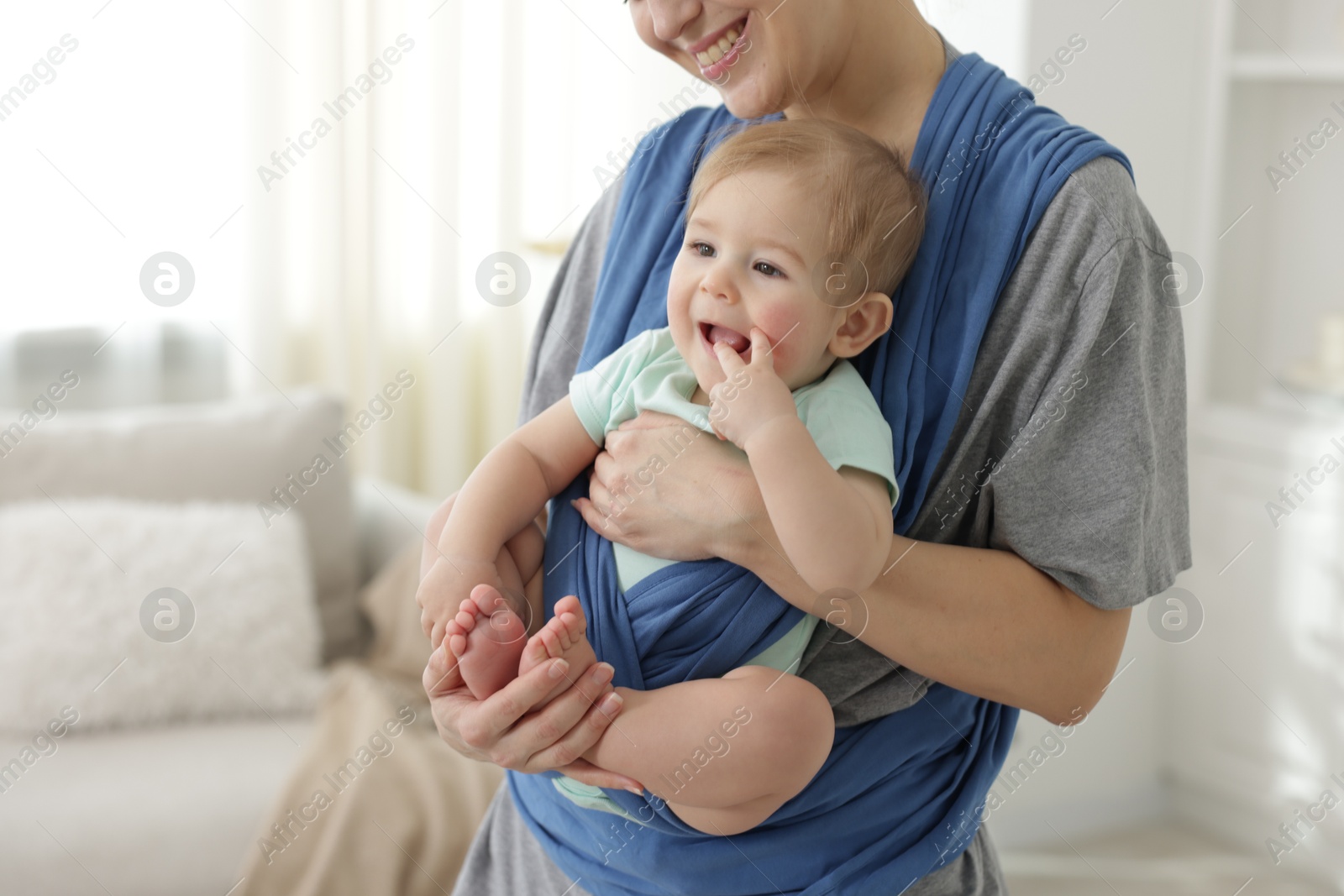 Photo of Mother holding her child in sling at home, closeup. Space for text