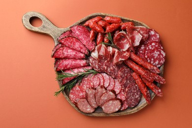 Different smoked sausages slices on orange background, top view