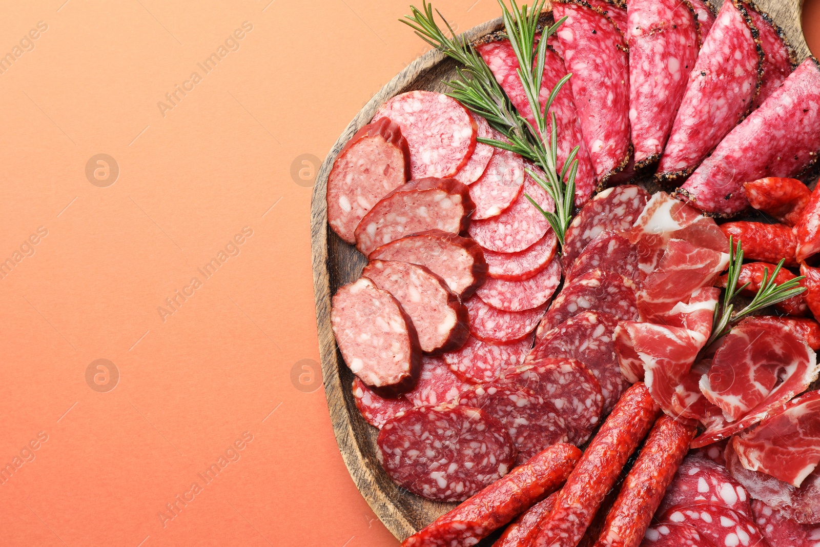 Photo of Different smoked sausages slices on orange background, top view. Space for text