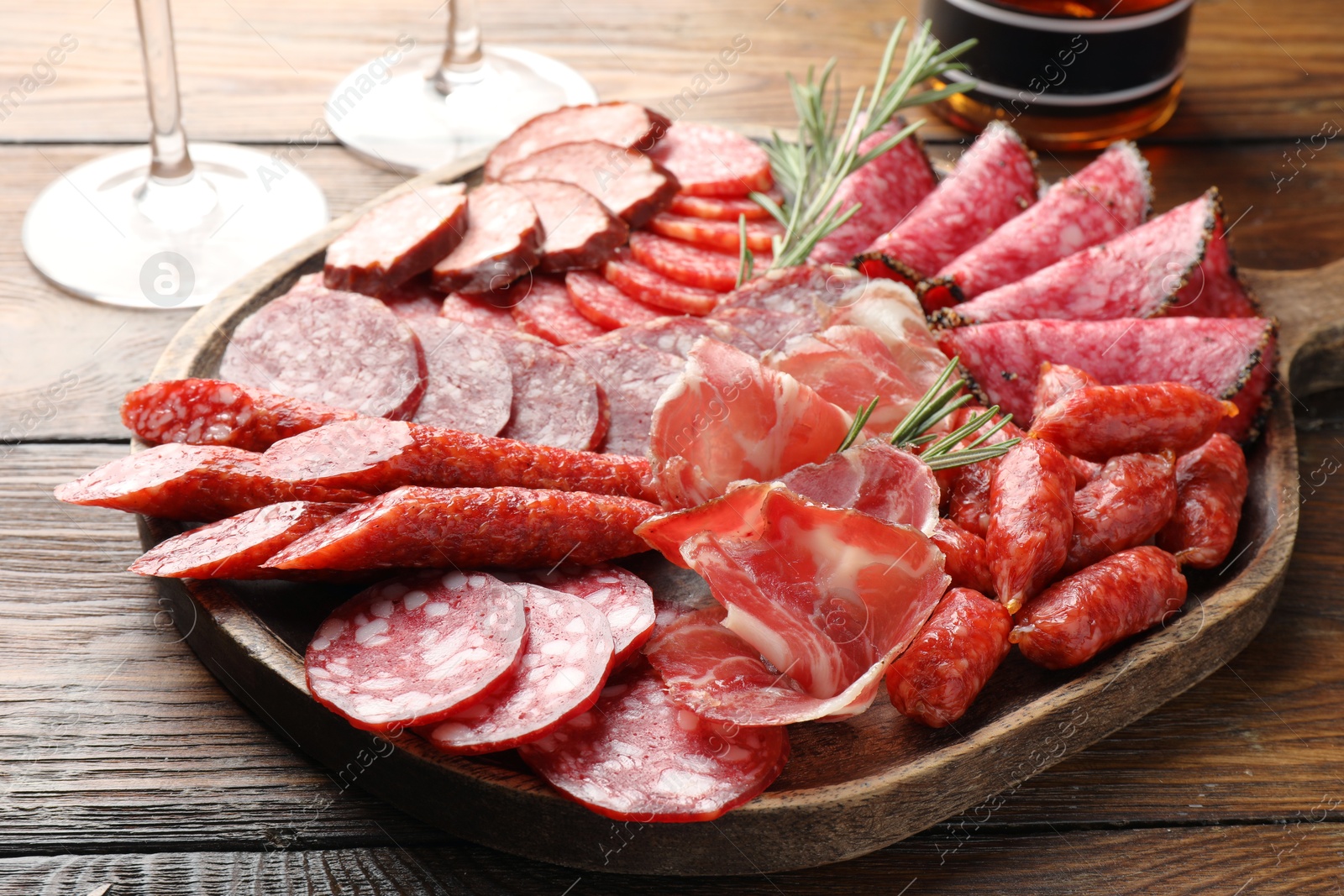 Photo of Different smoked sausages slices served on wooden table closeup